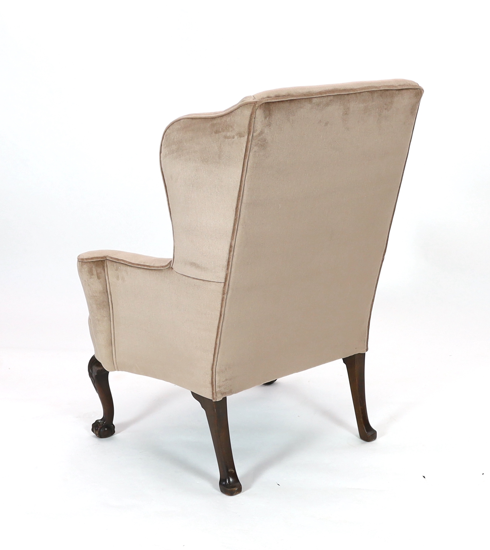 A George II style mahogany wing armchair, upholstered in beige dralon, on acanthus carved cabriole legs with claw and ball feet, 93cm wide, 80cm deep, 114cm high. Condition - good